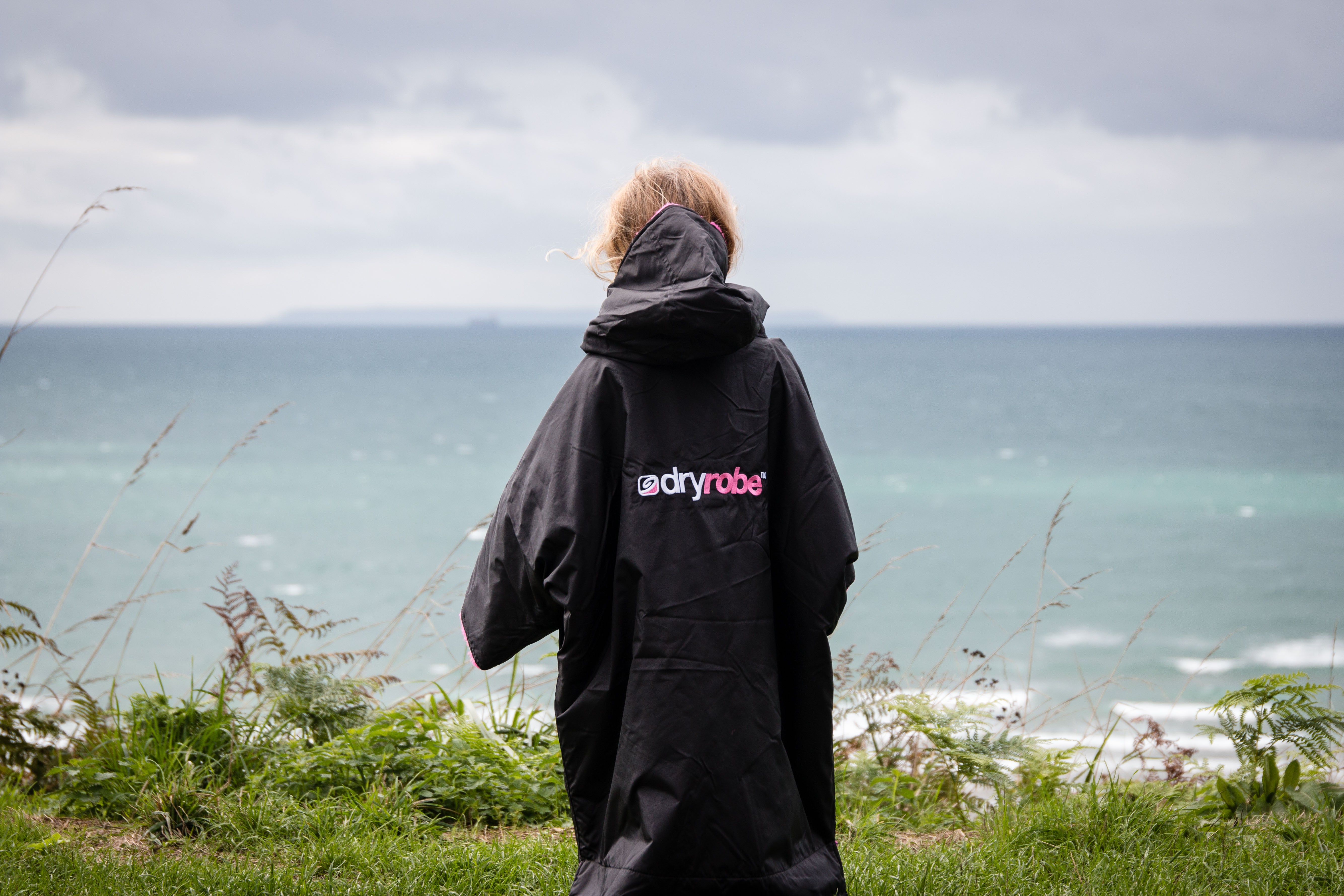 Girl in dryrobe at the shoreline 