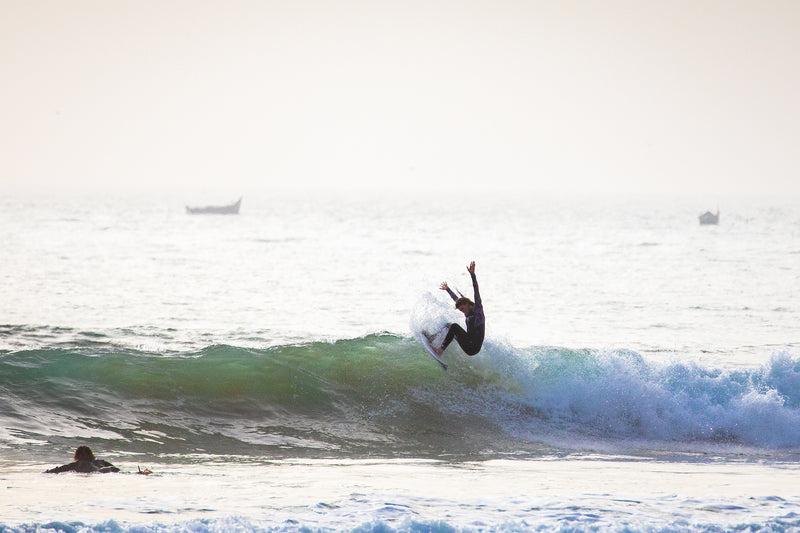 Lucy Campbell riding a wave with hands in the air