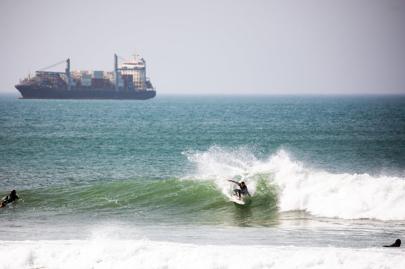 Lucy Campbell surfing with a ship in the background 