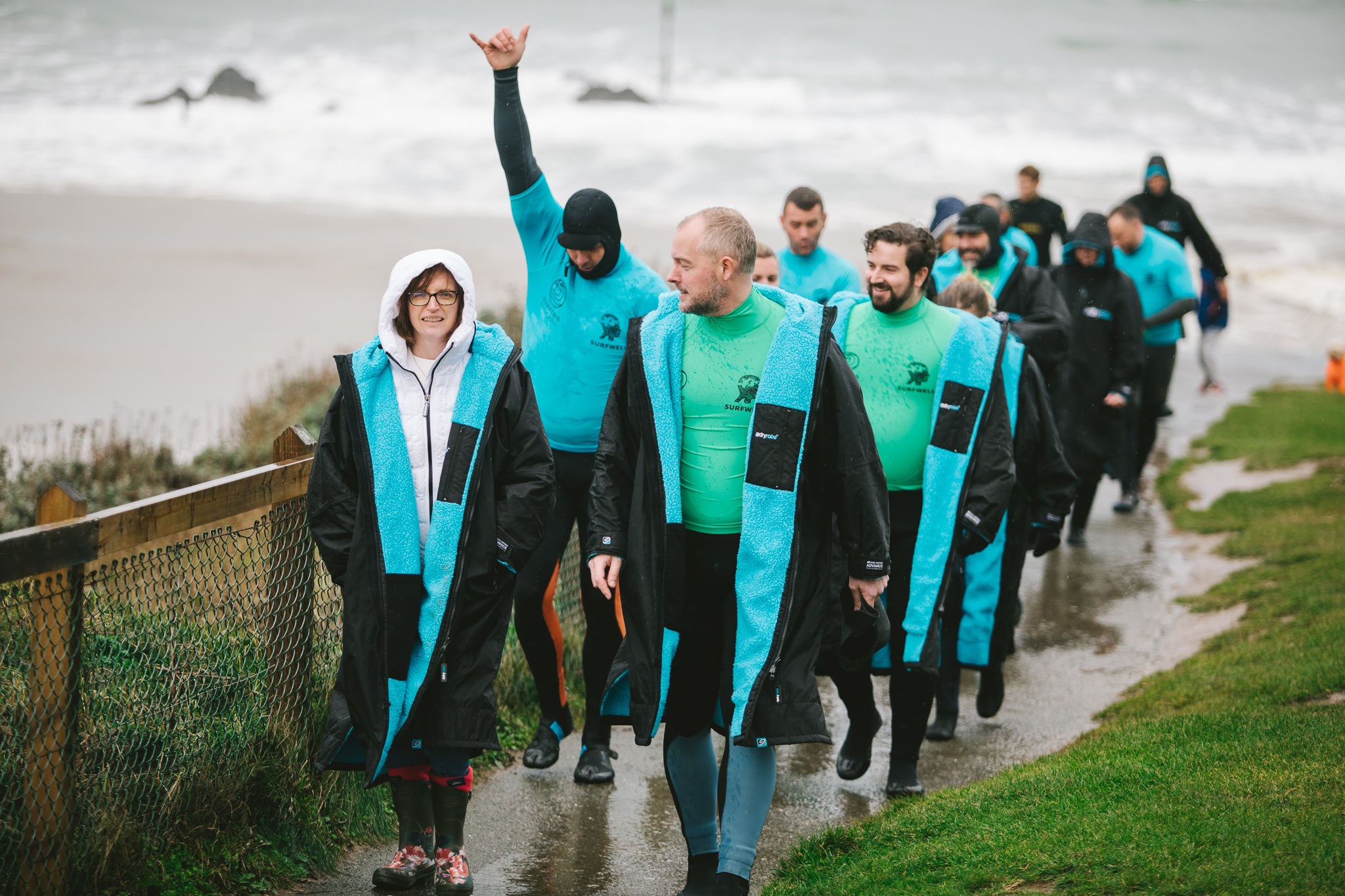 Surfwell surf therapy participants walking from the beach wearing black and blue dryrobes