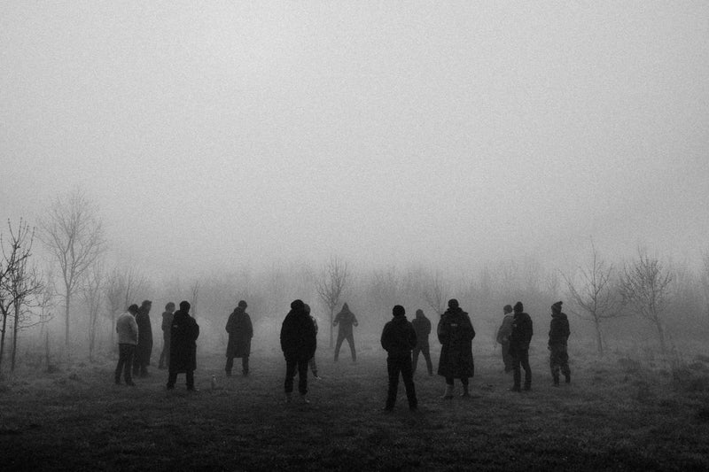 A black and white image of men standing around in a circle in the mist