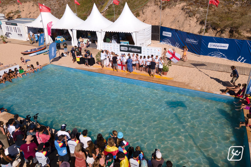 Team England Juniors stood together by a pool holding the English flag at the Euro Surf Junior Champs 2022