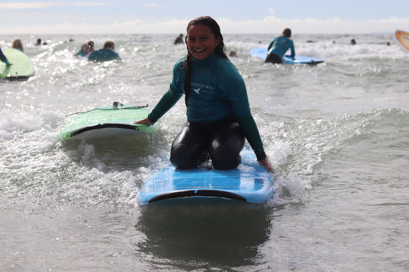 A young surfer kneeling on a surfboard catching a wave