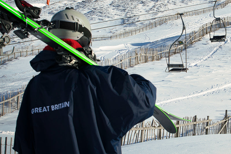 Skier carrying skis whilst wearing Team GB dryrobe® Advance
