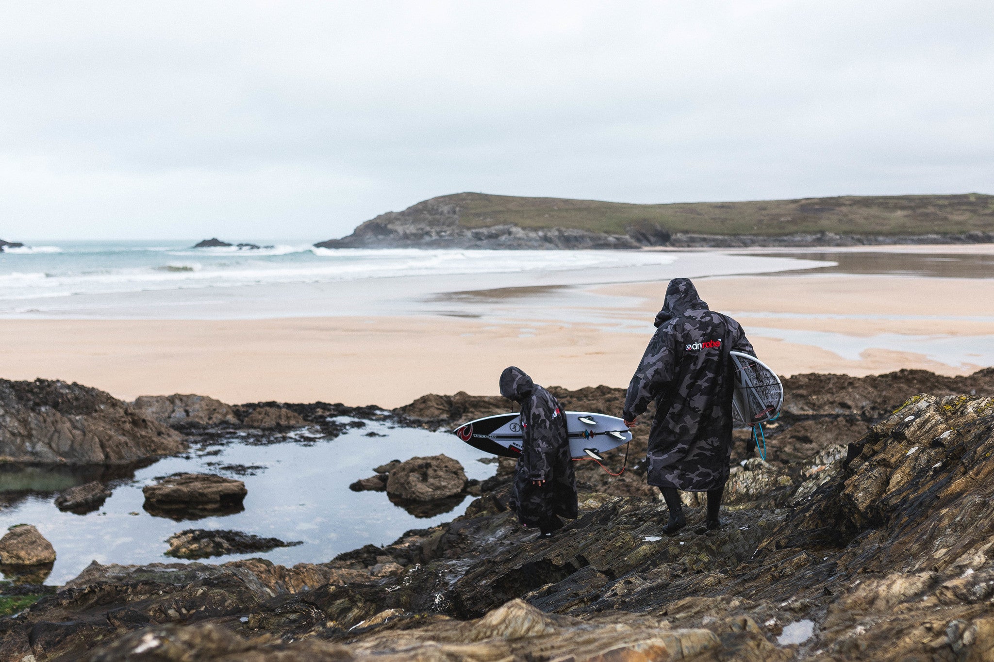 Ben and Lukas Skinner walking to the beach carrying surfboards whilst wearing dryrobe Advance Change Robes