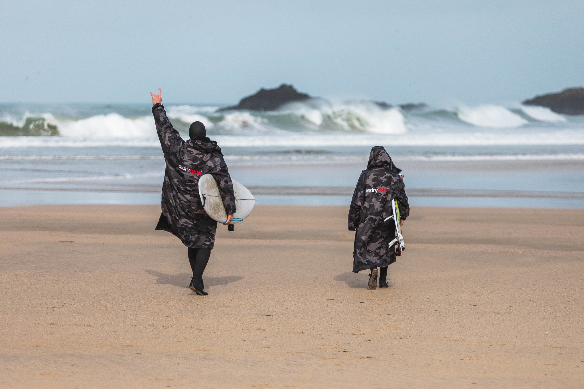 Lukas and Ben Skinner on beach walking towards the waves carrying surfboards