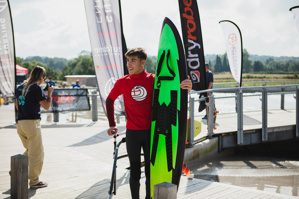 Competitor getting ready to to get into the water at the 2021 dryrobe English Adaptive Surfing Open
