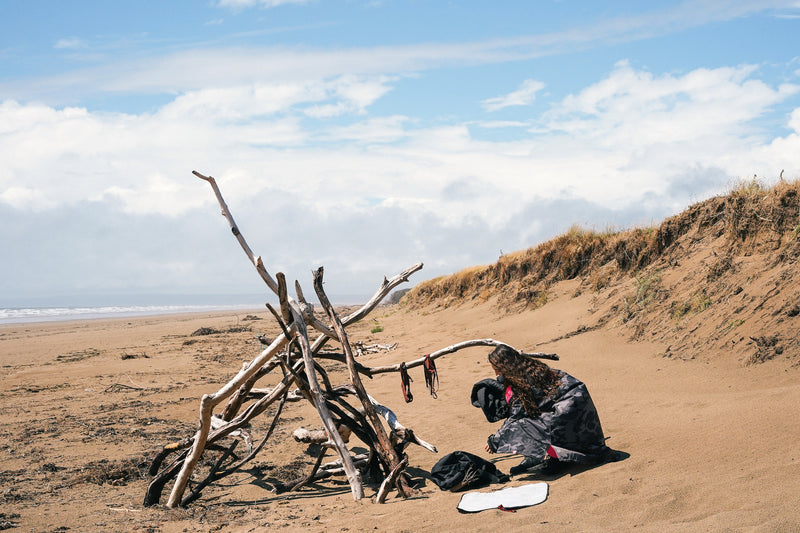 Woman on a sandy beach getting changed in a dryrobe Advance changing robe