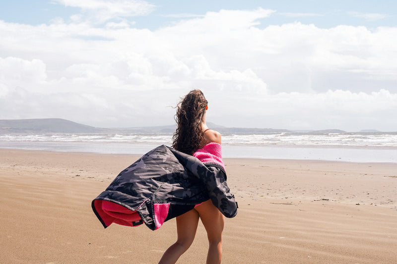 Women on the beach looking out to see wearing a dryrobe advance changing robe