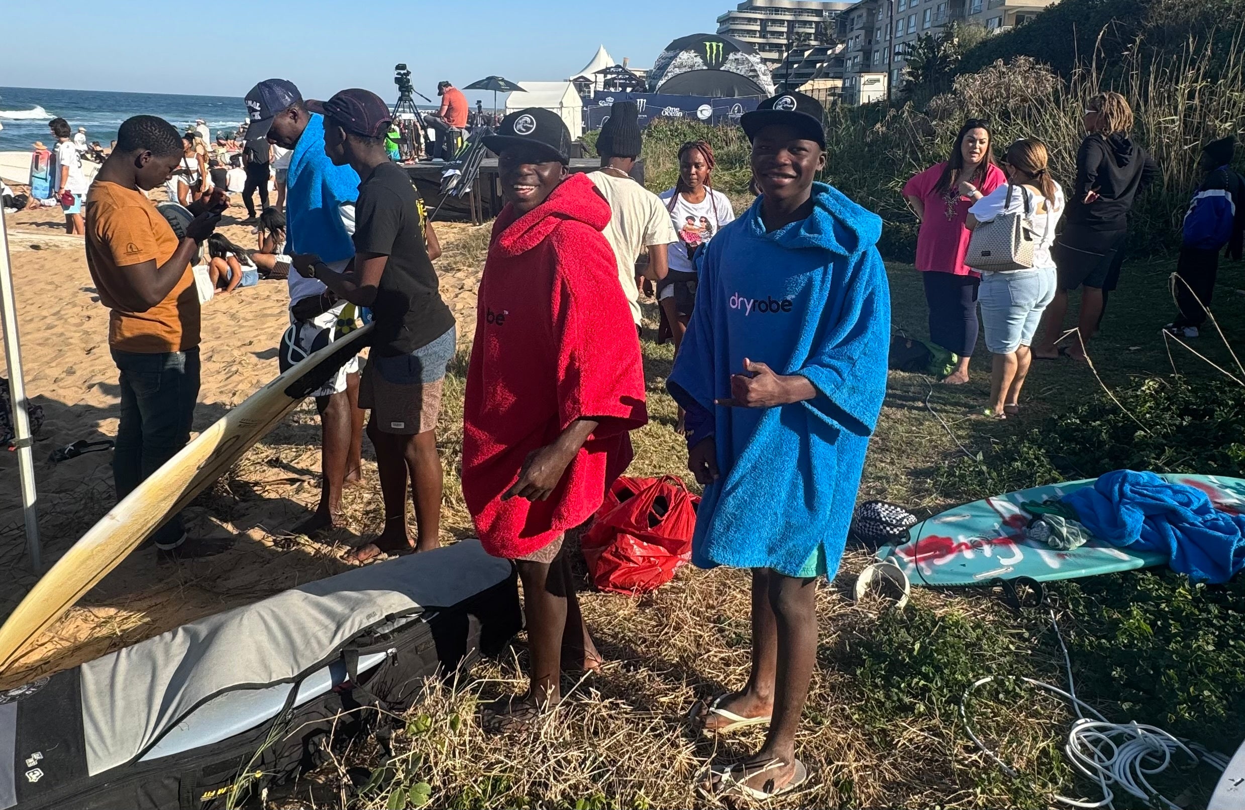 Two surfers from Surfers Not Street Children smiling in a red and blue towel robe on the beach