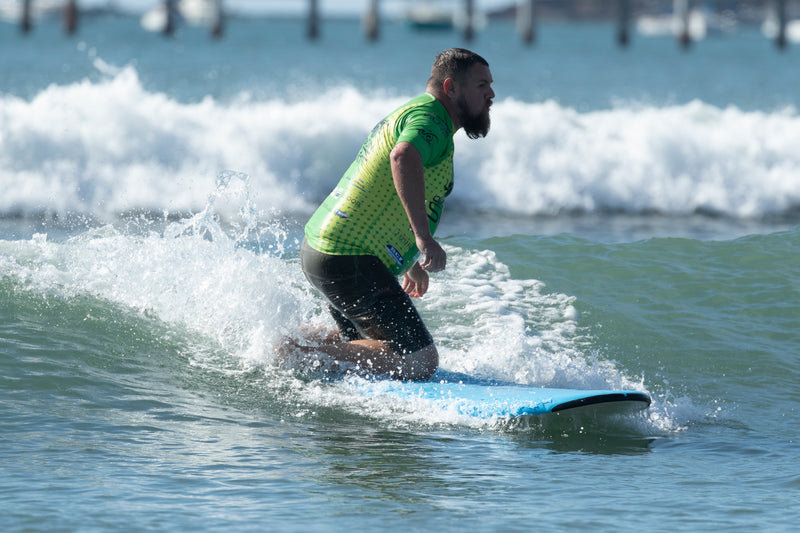 Surfer riding a wave in green rash vest 