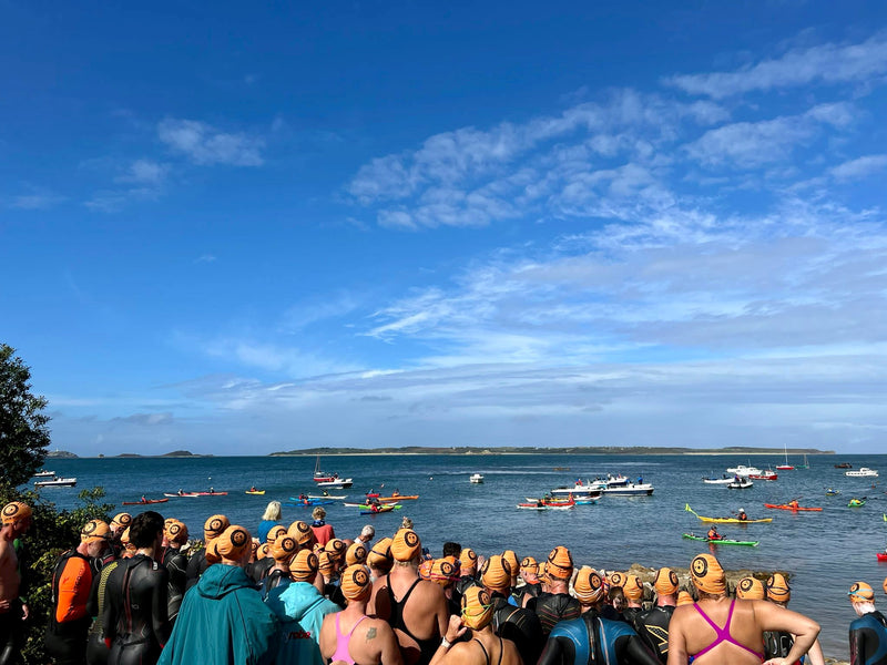 Swimmers lining up to go in the sea in orange swim caps 