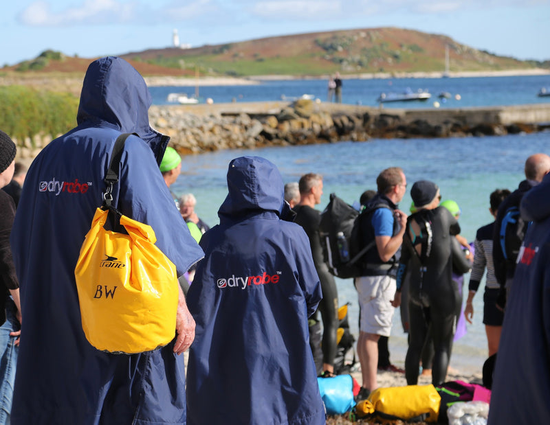 Swimmers walking down to the beach on the Isles of Scilly wearing navy dryrobes 