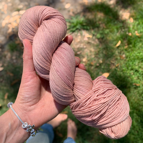 Birds Eye view of hand holding a pink skein of hand-dyed sock yarn