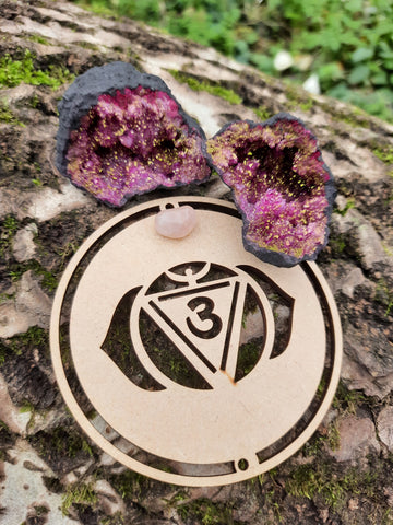 Tree trunk with on top our wooden third eye chakra symbol and red geode quartz