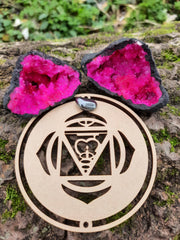 Tree trunk with on top our wooden root chakra symbol and pink quartz geode