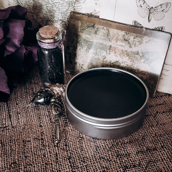 black ointment in silver tin 2 oz, tear drop charm with obsidian and key, black salt in 10 ml jar with cork top. Vintage background. 