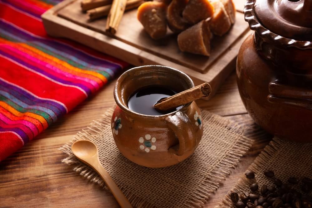 Mexican Cafe de Olla coffee on a cup with coffee beans and cinnamon sticks