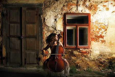 Vrouw speelt op een cello voor een huis