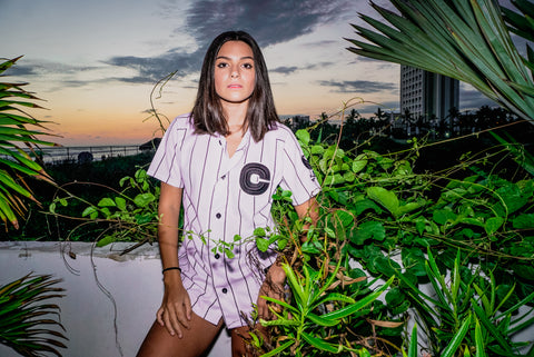 Girl wearing Referee II jersey standing on balcony as sun sets.