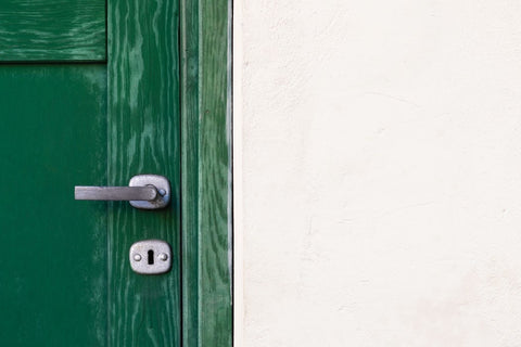 Image of a green door against a white stone wall. 