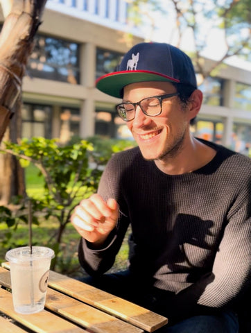 Tall darkhaired man with his coffee smiling in the sun in the park at a coffee shop in Beverly Hills, Los Angeles, California. Stella Coffee.