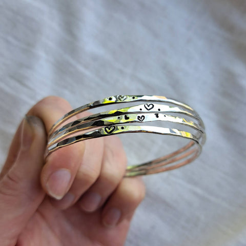 Four handmade silver bangles with hearts and initials, made in jewellery workshop