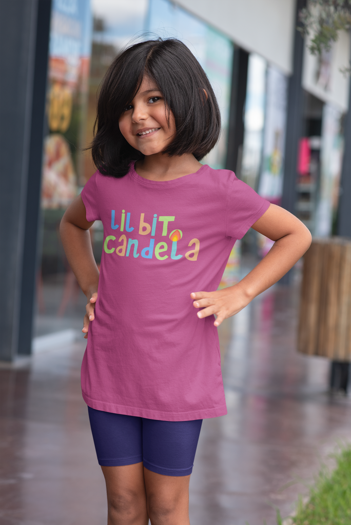 little hispanic girl standing in front of a store wearing a bright pink lil bit candela cuban t-shirt