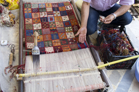 man showing a rug being hand made