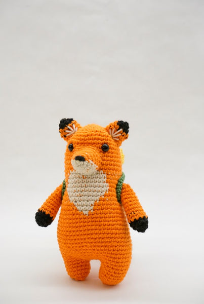 A crocheted fox with a backpack.