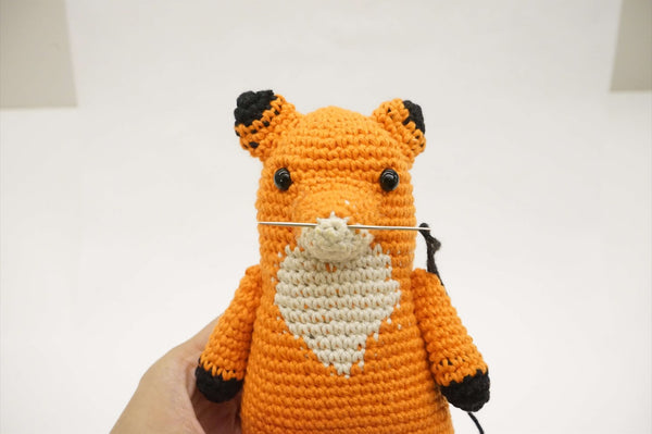 A crocheted fox’s arms.