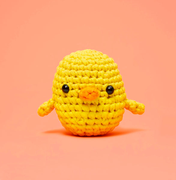 A yellow chick crochet plushie on an orange background