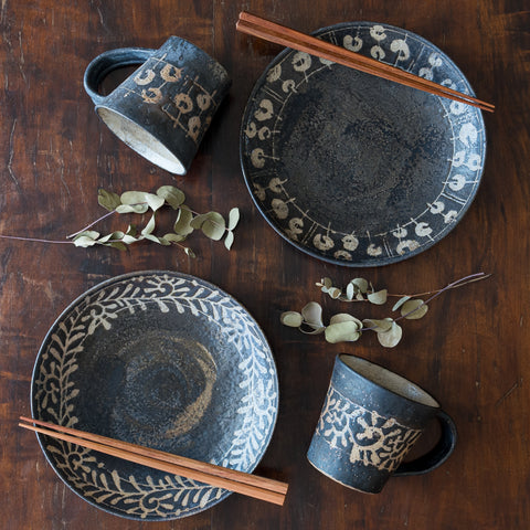 Nobufumi Watanabe's black-glazed vessels and mugs gracefully decorate the dining table.