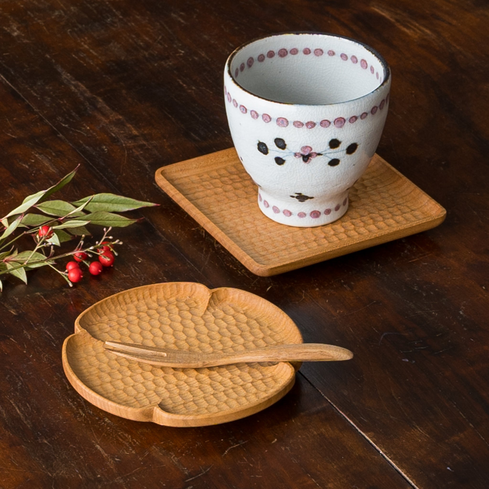 A flower-shaped coaster designed by Kazunori Gentakatsuka, a wonderful wooden workshop with a small snack on it.