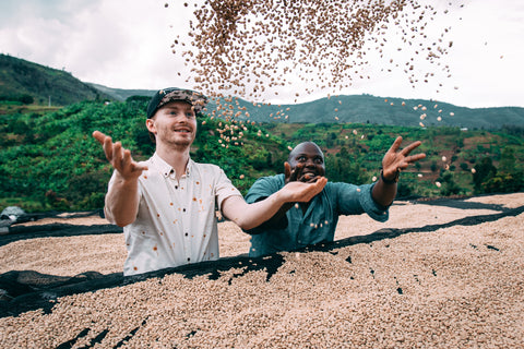 Cole Torode and Emmanuel tossing dried green coffee beans in the air