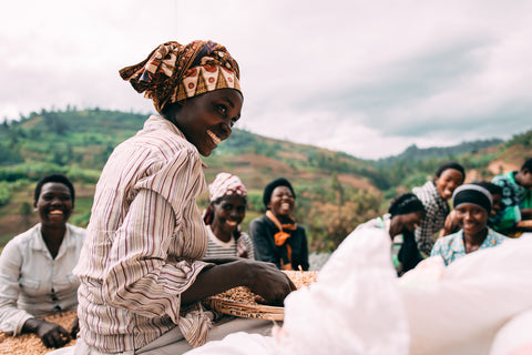 Female MTCo Station workers smiling and sorting green coffee beans