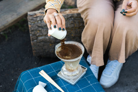Pouring Aeropress grinds into Clever Dripper for camping coffee
