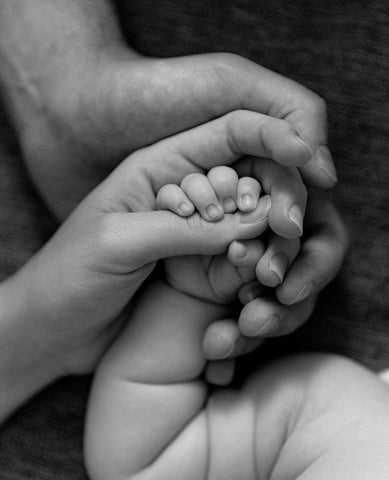 Mother and father holding their baby's hand