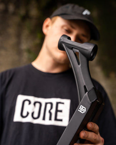 Mann hält einen Core Stunt Scooter