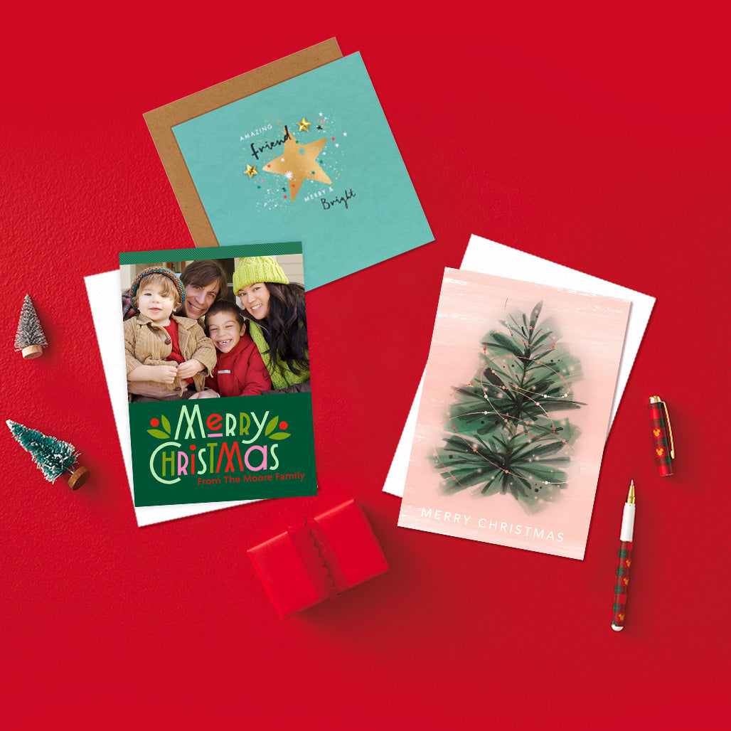 A red background, with a photo upload of a family on a green Christmas card with the message 'Merry Christmas from the Moore Family' in red text, two christmas tree decorations on the left.