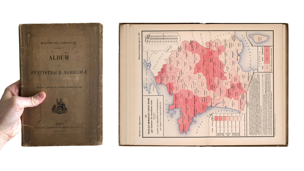 Holding up a copy of the 7.0 × 10.5 inch Album de statistique agricole, shown with one of its full-spread choropleth maps. 