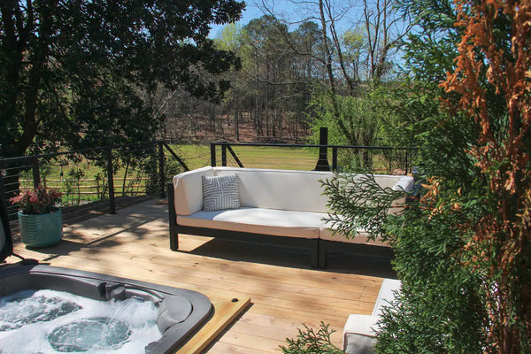 A hot tub and patio set up outside of a cabin.