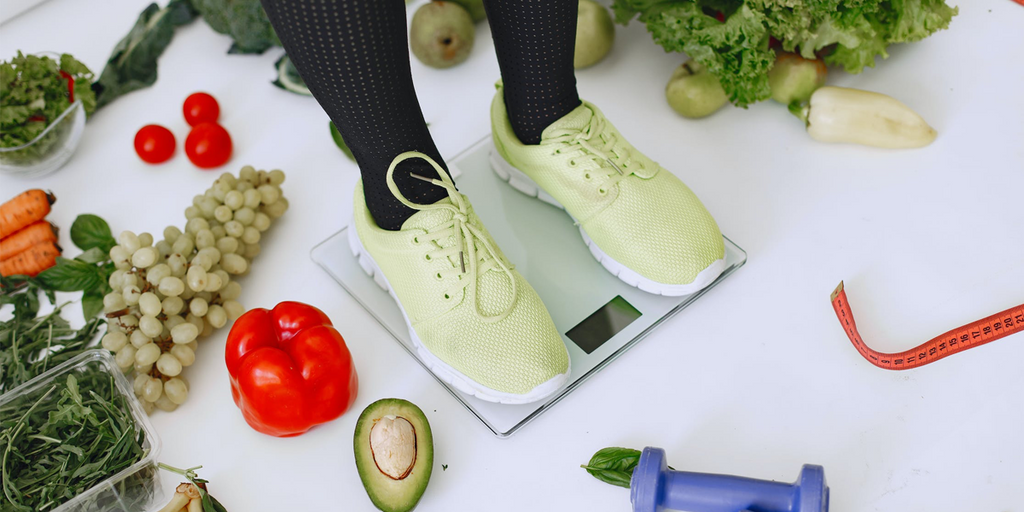 woman on weight scales surrounded by healthy foods