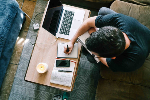 view from above of a man taking notes next to his laptop