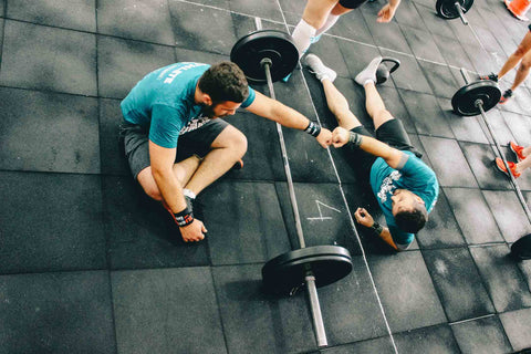 Two men fist bumping over a barbell