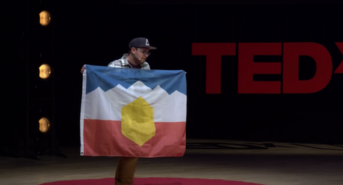 Michael Green holding his redesigned Utah flag at TEDxUSU in Logan, Utah.