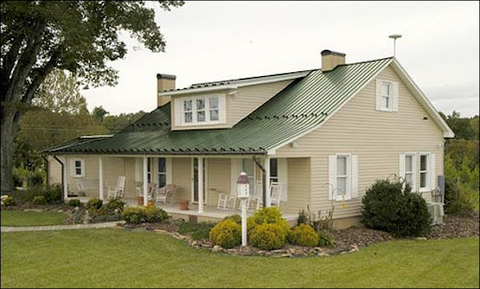 Tan brick house with green metal roof