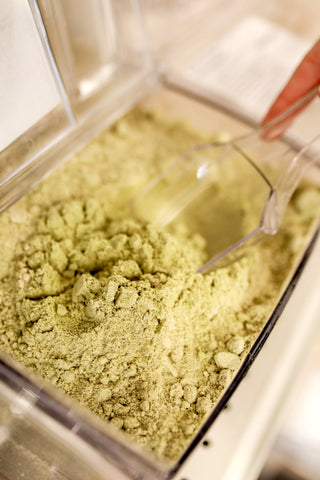 A photo of a green tea powder mixture with a plastic scoop stuck inside