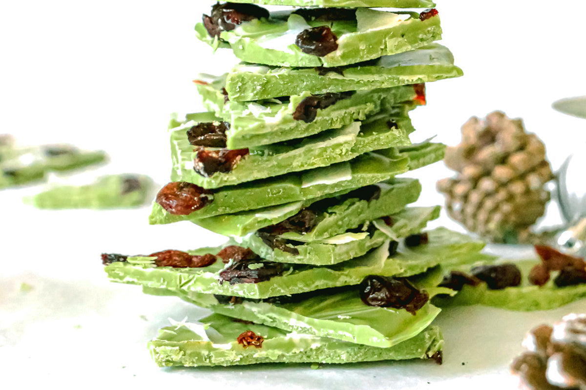 Photo of a stack of pieces of green tea Holiday Bark dessert treats topped with cranberries and white coconut strips, all on a white background