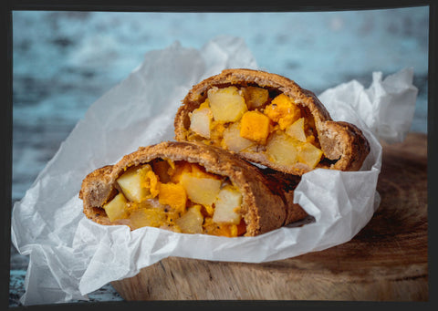 Vegan roast veg pasty cut open to reveal tasty filling. Chunk of Devon